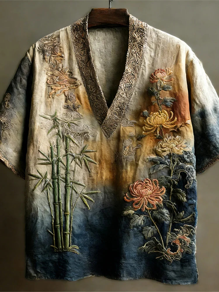 A linen v-neck shirt with intricate floral, bamboo, and nature-inspired embroidery in earth tones and blue gradients.