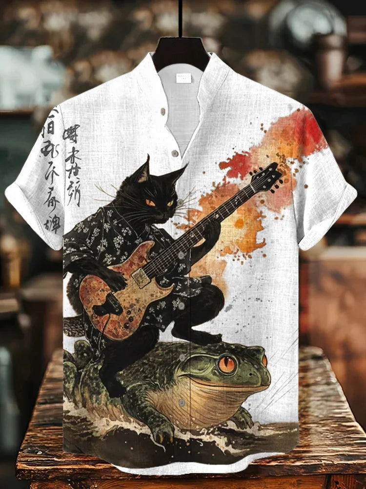 Short-sleeve button-up shirt with black cat playing guitar atop a frog, artistic paint splatter design.