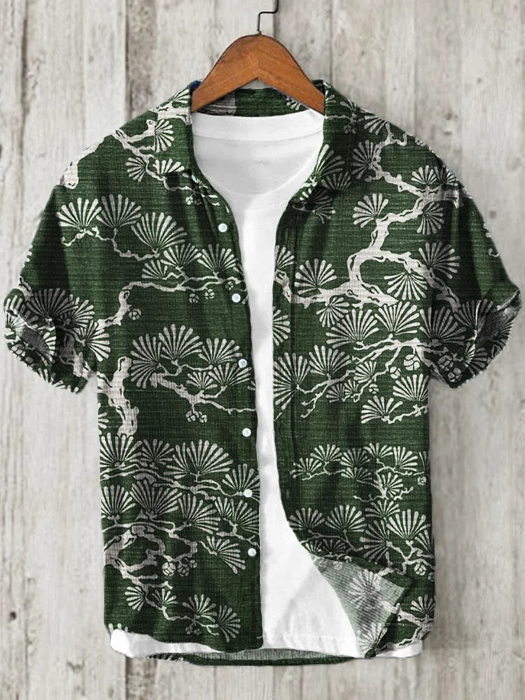 Green short sleeve shirt with white botanical tree and leaf print displayed on a hanger.